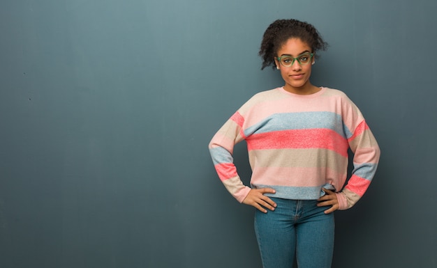 Young african american girl with blue eyes with hands on hips