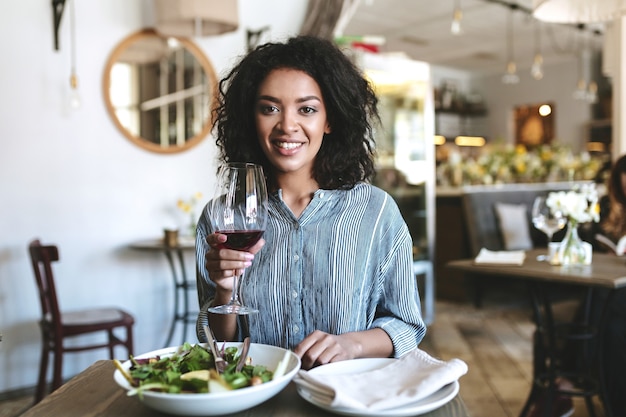 Young African American girl with dark curly hair sitting in restaurant