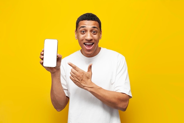 Young african american guy in white tshirt shows blank screen of smartphone