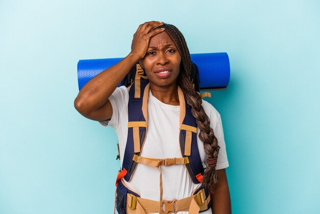 Young african american hiker woman isolated on blue background being shocked, she has remembered important meeting.