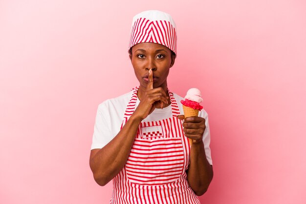 Giovane donna afroamericana del gelatiere che tiene il gelato isolato su sfondo rosa mantenendo un segreto o chiedendo silenzio.