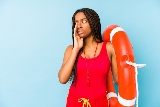 Young african american life guard woman isolated is saying a secret hot braking news and looking aside