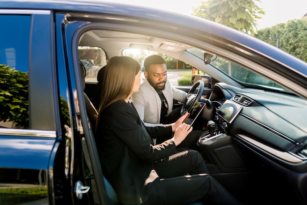 Photo young african american man communicating with female caucasian coworker during car drive to business meeting