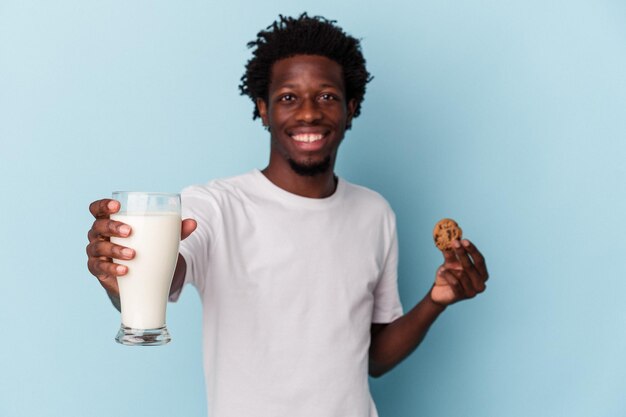 チョコレートチップクッキーを食べて、青でミルクを飲む若いアフリカ系アメリカ人の男