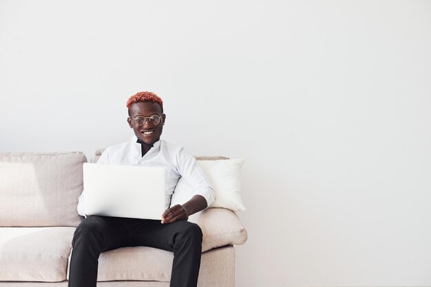 Young african american man in formal clothes sitting indoors with laptop in hands