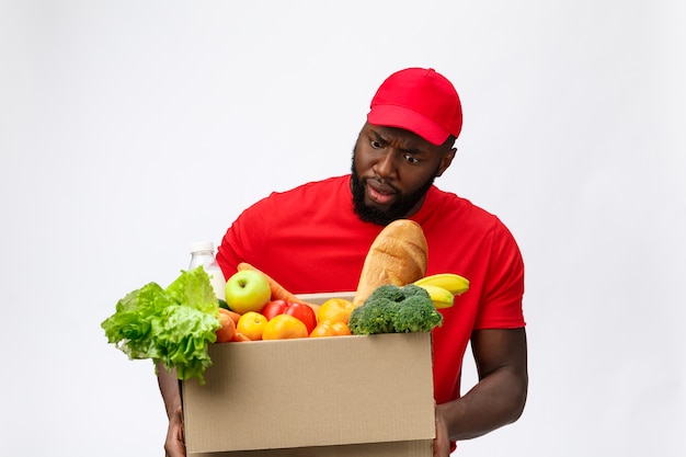 衝撃的な顔で手に食料品の箱を持っている若いアフリカ系アメリカ人の男。