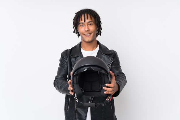 Young african american man holding a motorcycle helmet isolated on white wall with happy expression