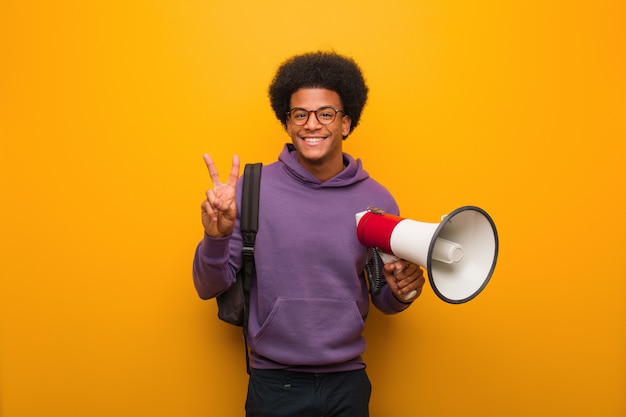 Photo young african american man holdinga a megaphone showing number two