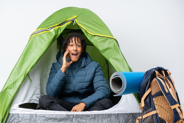 Photo young african american man inside a camping green tent with surprise and shocked facial expression