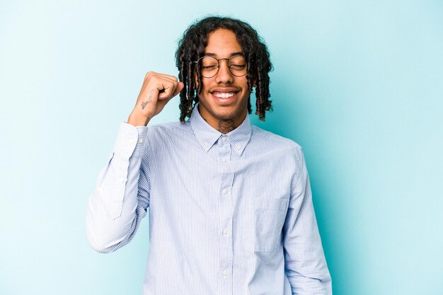 Young African American man isolated on blue background celebrating a victory passion and enthusiasm happy expression