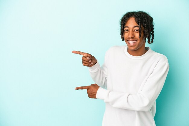 Young african american man isolated on blue background excited pointing with forefingers away.