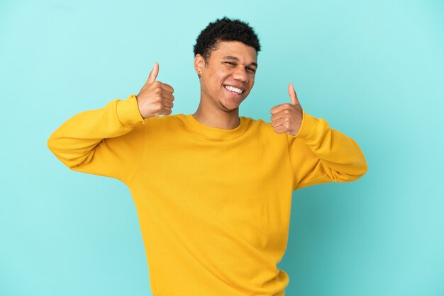 Photo young african american man isolated on blue background giving a thumbs up gesture