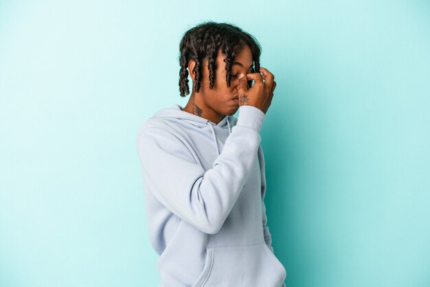 Young african american man isolated on blue background having a head ache, touching front of the face.