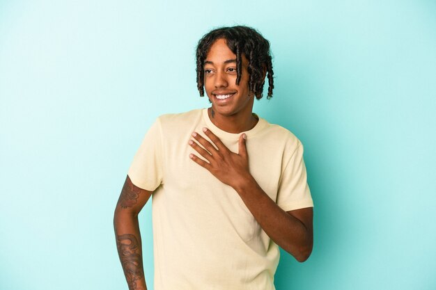 Young african american man isolated on blue background laughing keeping hands on heart, concept of happiness.