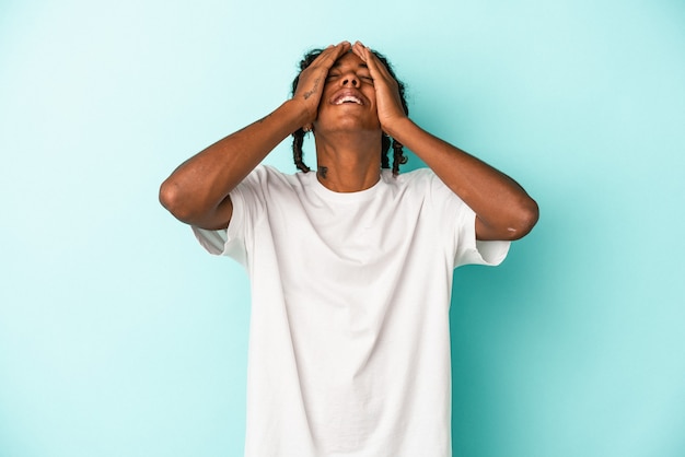 Young african american man isolated on blue background laughs joyfully keeping hands on head. Happiness concept.