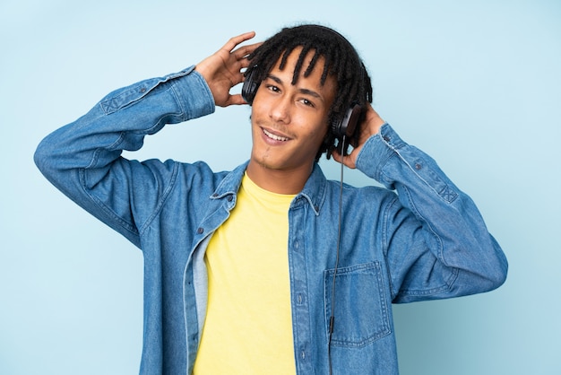 Young african american man isolated on blue background listening music