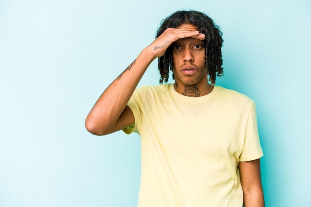 Young African American man isolated on blue background looking far away keeping hand on forehead