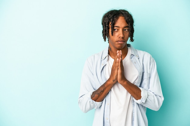 Young african american man isolated on blue background making up plan in mind, setting up an idea.