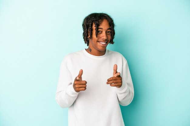 Young african american man isolated on blue background pointing to front with fingers.