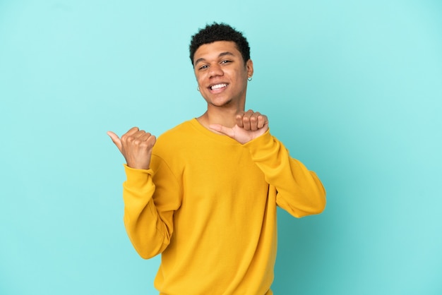 Young African American man isolated on blue background pointing to the side to present a product