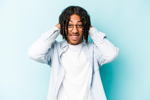 Young African American man isolated on blue background screaming with rage