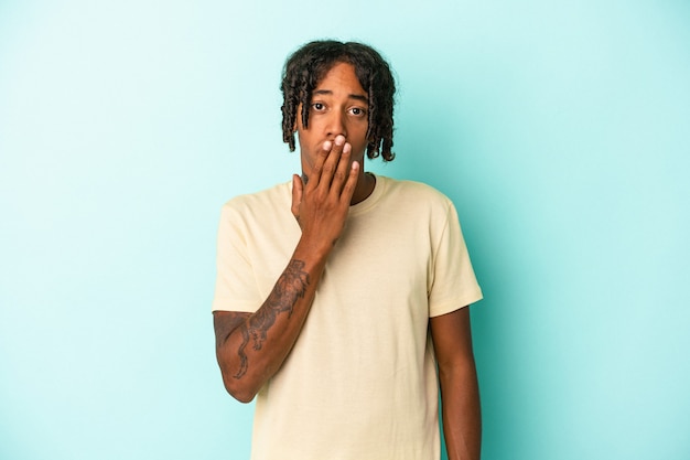 Young african american man isolated on blue background shocked, covering mouth with hands, anxious to discover something new.