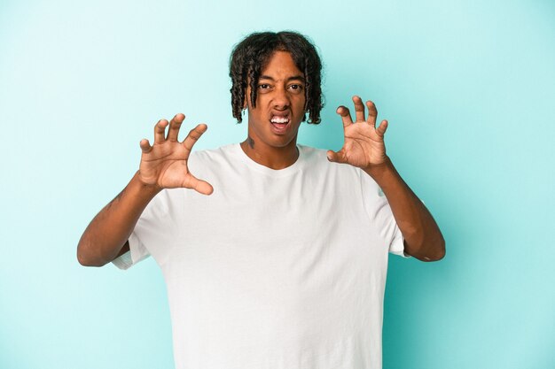 Young african american man isolated on blue background showing claws imitating a cat, aggressive gesture.