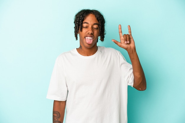 Young african american man isolated on blue background showing rock gesture with fingers