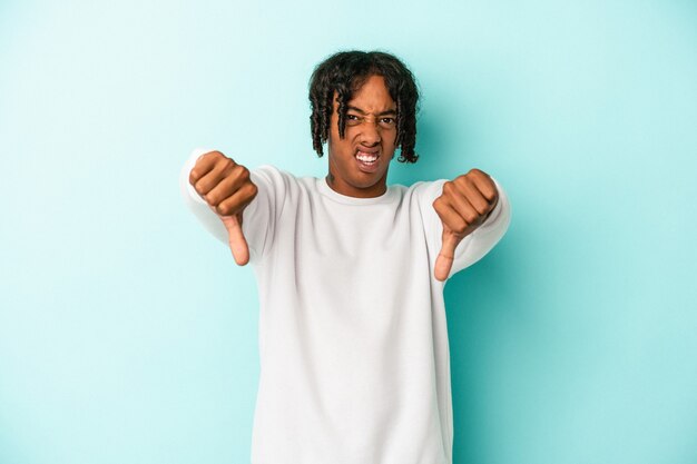 Young african american man isolated on blue background showing thumb down and expressing dislike.