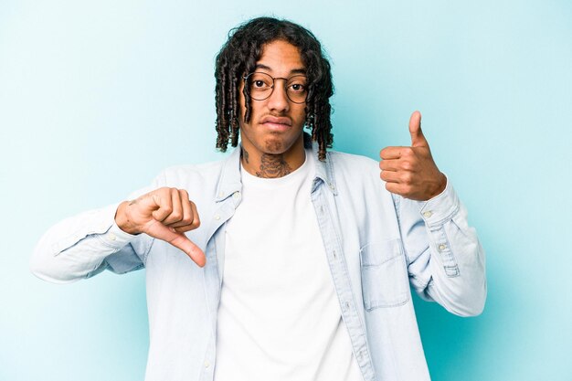 Young African American man isolated on blue background showing thumbs up and thumbs down difficult choose concept