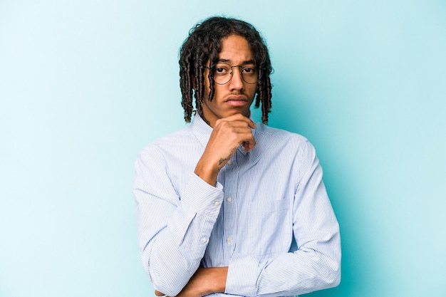 Young African American man isolated on blue background thinking and looking up being reflective contemplating having a fantasy