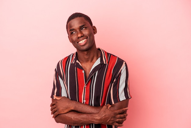 Young African American man isolated on pink background dreaming of achieving goals and purposes
