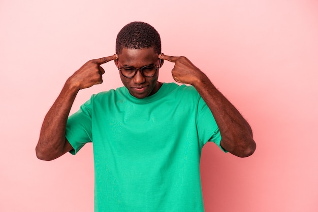 Young African American man isolated on pink background focused on a task, keeping forefingers pointing head.