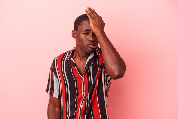Young African American man isolated on pink background forgetting something, slapping forehead with palm and closing eyes.