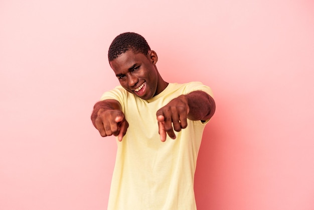 Young African American man isolated on pink background pointing to front with fingers.