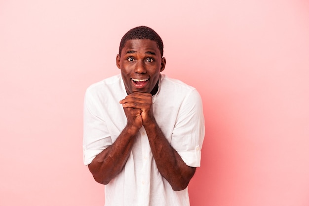 Young African American man isolated on pink background praying for luck amazed and opening mouth looking to front