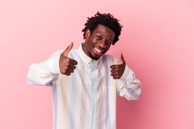 Young african american man isolated on pink background raising both thumbs up, smiling and confident.