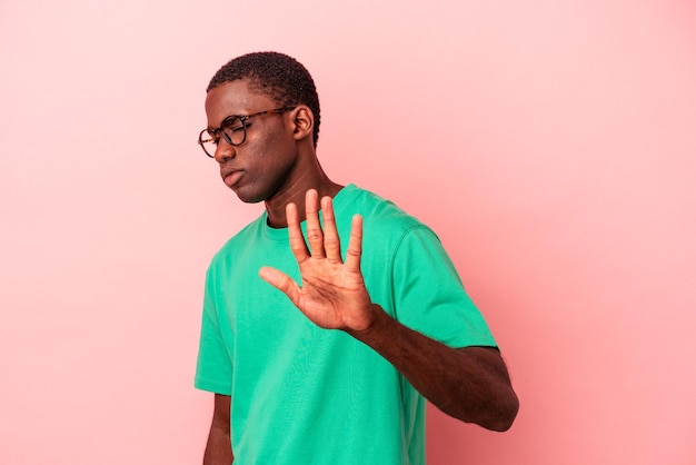 Young African American man isolated on pink background rejecting someone showing a gesture of disgust.