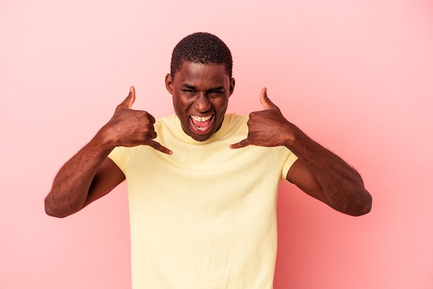 Young African American man isolated on pink background showing a mobile phone call gesture with fingers.