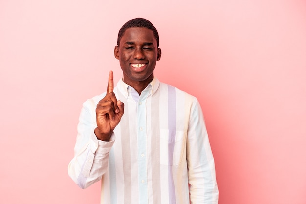 Young African American man isolated on pink background showing number one with finger.