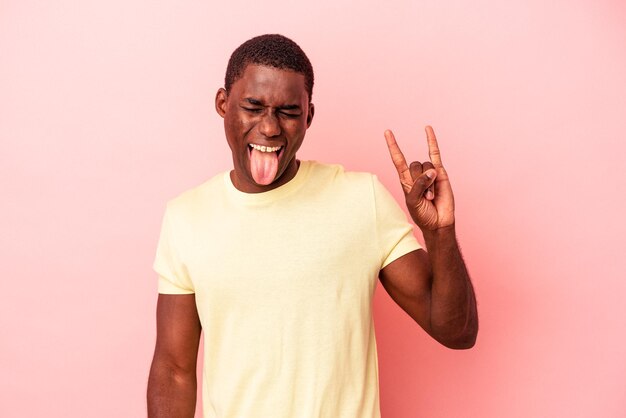 Young African American man isolated on pink background showing rock gesture with fingers