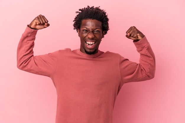 Young african american man isolated on pink background showing strength gesture with arms, symbol of feminine power