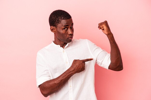 Young African American man isolated on pink background showing strength gesture with arms, symbol of feminine power