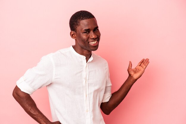 Young African American man isolated on pink background showing a welcome expression.