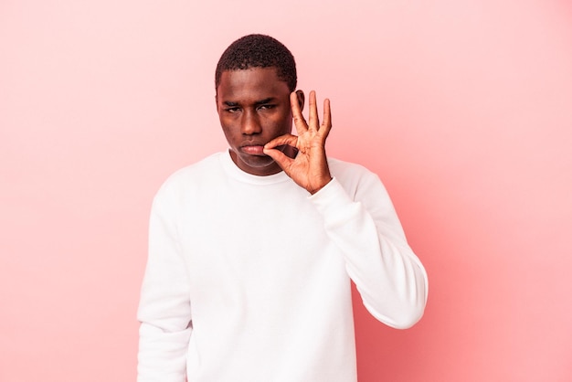 Photo young african american man isolated on pink background with fingers on lips keeping a secret.