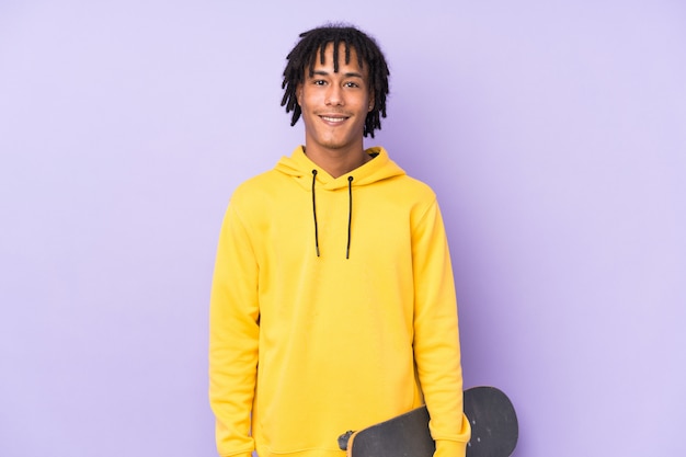 Photo young african american man isolated on purple background with a skate