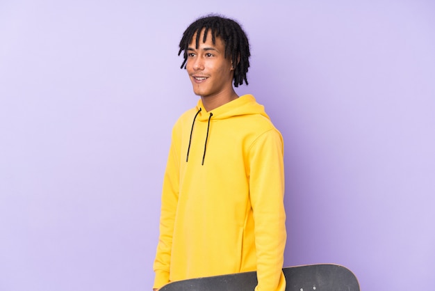 Photo young african american man isolated on purple with a skate