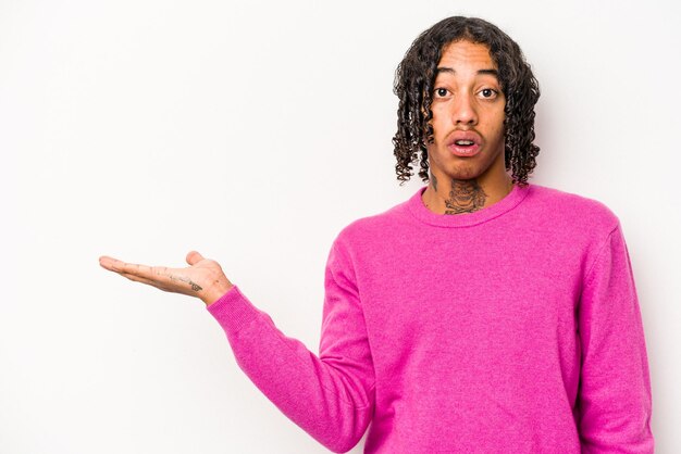 Young African American man isolated on white background impressed holding copy space on palm