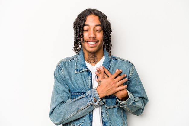 Young African American man isolated on white background laughing keeping hands on heart concept of happiness