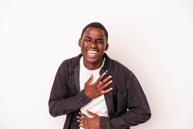 Young African American man isolated on white background laughs happily and has fun keeping hands on stomach.